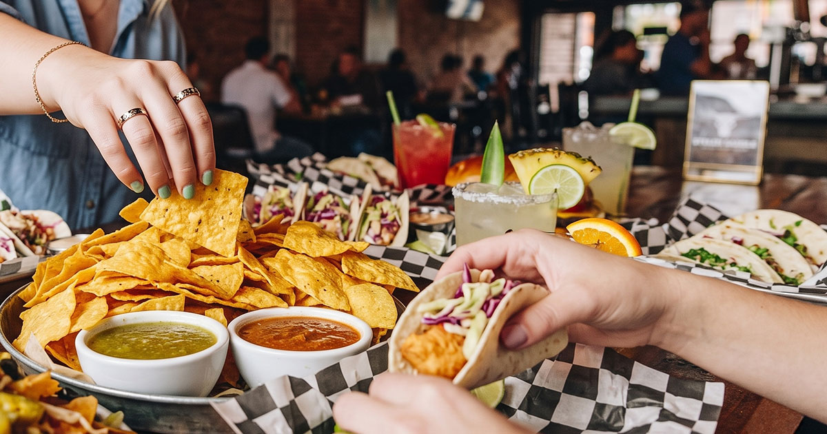 Friends sharing tacos, chips and cocktails at a Wrigleyville restaurant table